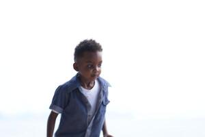 misturado raça africano e ásia Garoto é jogando às a ao ar livre área. sorridente feliz Garoto tem Diversão corrida em a de praia. retrato do Garoto estilo de vida com uma único Penteado. foto