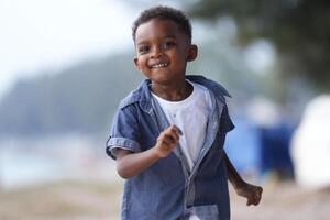 misturado raça africano e ásia Garoto é jogando às a ao ar livre área. sorridente feliz Garoto tem Diversão corrida em a de praia. retrato do Garoto estilo de vida com uma único Penteado. foto