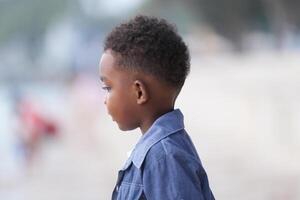 misturado raça africano e ásia Garoto é jogando às a ao ar livre área. sorridente feliz Garoto tem Diversão corrida em a de praia. retrato do Garoto estilo de vida com uma único Penteado. foto