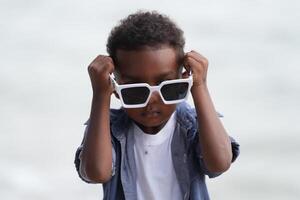 misturado raça africano e ásia Garoto é jogando às a ao ar livre área. sorridente feliz Garoto tem Diversão corrida em a de praia. retrato do Garoto estilo de vida com uma único Penteado. foto