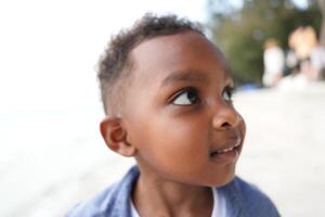 misturado raça africano e ásia Garoto é jogando às a ao ar livre área. sorridente feliz Garoto tem Diversão corrida em a de praia. retrato do Garoto estilo de vida com uma único Penteado. foto