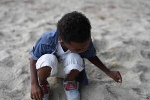 misturado raça africano e ásia Garoto é jogando às a ao ar livre área. sorridente feliz Garoto tem Diversão corrida em a de praia. retrato do Garoto estilo de vida com uma único Penteado. foto