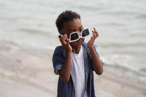 misturado raça africano e ásia Garoto é jogando às a ao ar livre área. sorridente feliz Garoto tem Diversão corrida em a de praia. retrato do Garoto estilo de vida com uma único Penteado. foto