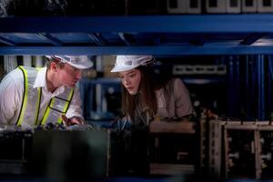 técnico engenheiros equipe verificação a máquina e manutenção serviço. trabalhadores olhando às poupar partes dentro estoque às armazém fábrica. trabalhador com uma lista de controle olhando em parte do máquina peças. foto