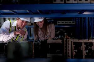 técnico engenheiros equipe verificação a máquina e manutenção serviço. trabalhadores olhando às poupar partes dentro estoque às armazém fábrica. trabalhador com uma lista de controle olhando em parte do máquina peças. foto