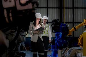 o negócio mulher e homem encontro e verificação Novo máquina robô. engenheiro caminhando às armazém indústria máquina. o negócio negociação conceitos e tecnologia. mulher é usando inteligente tábua para presente cara. foto