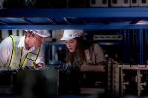 técnico engenheiros equipe verificação a máquina e manutenção serviço. trabalhadores olhando às poupar partes dentro estoque às armazém fábrica. trabalhador com uma lista de controle olhando em parte do máquina peças. foto