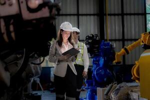 o negócio mulher e homem encontro e verificação Novo máquina robô. engenheiro caminhando às armazém indústria máquina. o negócio negociação conceitos e tecnologia. mulher é usando inteligente tábua para presente cara. foto