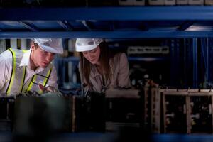 técnico engenheiros equipe verificação a máquina e manutenção serviço. trabalhadores olhando às poupar partes dentro estoque às armazém fábrica. trabalhador com uma lista de controle olhando em parte do máquina peças. foto