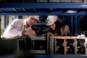 técnico engenheiros equipe verificação a máquina e manutenção serviço. trabalhadores olhando às poupar partes dentro estoque às armazém fábrica. trabalhador com uma lista de controle olhando em parte do máquina peças. foto