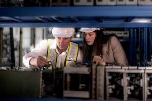 técnico engenheiros equipe verificação a máquina e manutenção serviço. trabalhadores olhando às poupar partes dentro estoque às armazém fábrica. trabalhador com uma lista de controle olhando em parte do máquina peças. foto