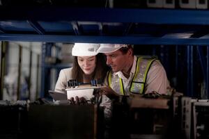 técnico engenheiros equipe verificação a máquina e manutenção serviço. trabalhadores olhando às poupar partes dentro estoque às armazém fábrica. trabalhador com uma lista de controle olhando em parte do máquina peças. foto