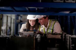 técnico engenheiros equipe verificação a máquina e manutenção serviço. trabalhadores olhando às poupar partes dentro estoque às armazém fábrica. trabalhador com uma lista de controle olhando em parte do máquina peças. foto