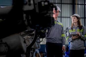 engenheiros Verifica ao controle pesado máquina robô braço. diverso equipe do industrial robótica engenheiros colhido por aí máquina. profissional maquinaria operadores reparar elétrico robô em brilhante digital painel. foto