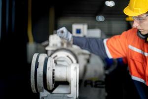 engenheiro homem verificação a status do máquina e usava chave inglesa para parafuso alguns parte do equipamento às cnc fábrica. trabalhador vestindo segurança óculos e capacete. manutenção e reparação conceito. foto