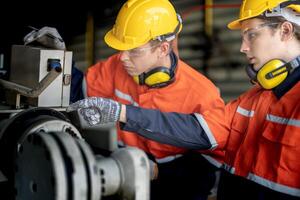 masculino engenheiro trabalhadores manutenção automático robótico braço máquina dentro uma fábrica. trabalhador verificação e reparação automático robô mão máquina. técnico trabalhador Verifica para reparar fábrica máquina. foto