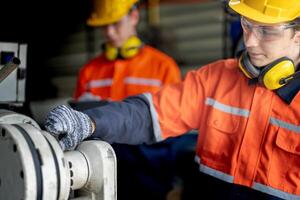 engenheiro homem verificação a status do máquina e usava chave inglesa para parafuso alguns parte do equipamento às cnc fábrica. trabalhador vestindo segurança óculos e capacete. manutenção e reparação conceito. foto