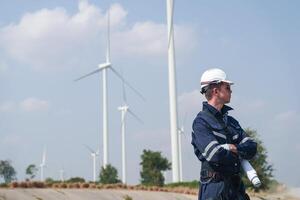 engenheiros trabalhando dentro trabalho de campo ar livre. trabalhadores caminhando e inspecionar construção e máquina por aí projeto local. vento turbina elétrico do limpar \ limpo recurso enérgico e meio Ambiente sustentável. foto