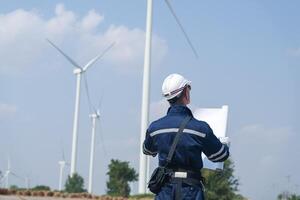 engenheiros trabalhando dentro trabalho de campo ar livre. trabalhadores caminhando e inspecionar construção e máquina por aí projeto local. vento turbina elétrico do limpar \ limpo recurso enérgico e meio Ambiente sustentável. foto