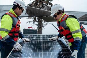 engenheiro homens inspecionar módulos do fotovoltaico célula painéis. industrial renovável energia do verde poder. trabalhadores preparar materiais antes construção em local com a pilha do painéis às fundo. foto