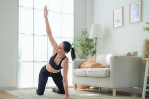 fechar acima mulheres confiante Treinamento ioga. Atlético mulheres dentro roupa de esporte fazendo ginástica alongamento exercícios às casa dentro a vivo sala. esporte e lazer conceito. ioga professor é ajudando garota. foto