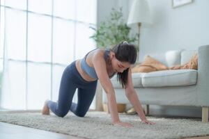 dois mulheres confiante Treinamento ioga. Atlético mulheres dentro roupa de esporte fazendo ginástica alongamento exercícios às casa dentro a vivo sala. esporte e lazer conceito. ioga professor é ajudando jovem mulher. foto