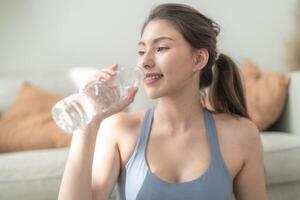 fechar acima do jovem face caucasiano ginástica mulher vestindo esporte roupas Treinamento interior bebendo fresco água. saudável estilo de vida e bem-estar. foto