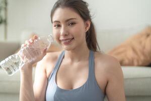 fechar acima do jovem face caucasiano ginástica mulher vestindo esporte roupas Treinamento interior bebendo fresco água. saudável estilo de vida e bem-estar. foto