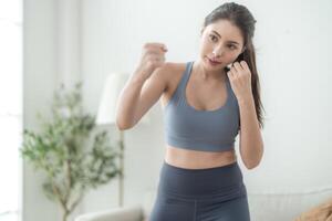 atraente e Forte mulher alongamento antes ginástica às interior casa. saudável estilo de vida. mulher caloroso acima de boxe dentro a ar. jovem fêmea com fino corpo soco boxe trabalho de pés cardio exercício. foto