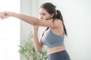 atraente e Forte mulher alongamento antes ginástica às interior casa. saudável estilo de vida. mulher caloroso acima de boxe dentro a ar. jovem fêmea com fino corpo soco boxe trabalho de pés cardio exercício. foto