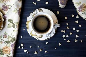 uma copo do café com decoração em uma Sombrio azul de madeira mesa topo visualizar. foto