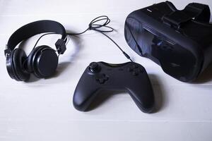 virtual realidade copos, controle de video game e fones de ouvido em uma branco fundo. foto