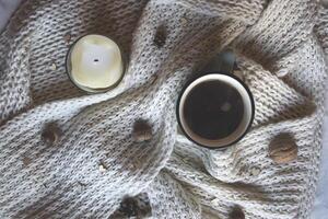 uma copo do café e de lã cachecol com decorações em uma mesa. conforto. foto