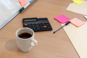 uma copo do café e uma calculadora em uma escrivaninha foto