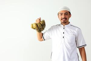 muçulmano masculino segurando pronto para comer ketupat, arroz bolo com diamante forma foto