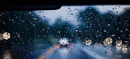 chuva chuveiro em carro parabrisa ou carro janela e embaçado estrada dentro fundo. foto