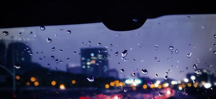 chuva chuveiro em carro parabrisa ou carro janela e embaçado estrada dentro fundo. foto