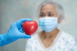 médico dá coração vermelho a paciente idosa ou idosa asiática, conceito médico forte e saudável foto