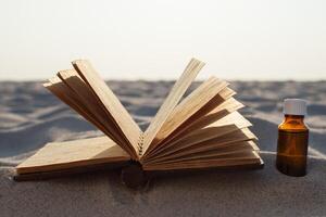 livro e essencial óleo em arenoso de praia foto