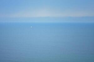 panorama com uma azul mar e uma barco a vela é visível dentro a distância foto