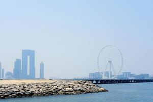 uma sereno Visão do a beira-mar dentro dubai, apresentando a silhueta do uma ampla ferris roda contra uma nebuloso céu. dubai, eua - agosto 15, 2023 foto