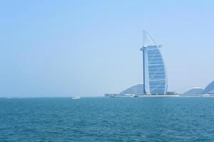 uma sereno Visão do a burj al árabe e a calma mar, com lazer barcos cruzeiro a águas do dubai. dubai, eua - agosto 15, 2023 foto