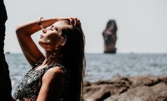 mulher verão viagem mar. feliz turista apreciar levando cenário ao ar livre para recordações. mulher viajante posando em a de praia às mar cercado de vulcânico montanhas, partilha viagem aventura viagem foto