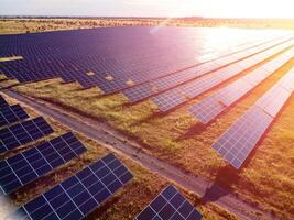 aéreo topo Visão do uma solar painéis poder plantar. fotovoltaico solar painéis às nascer do sol e pôr do sol dentro campo a partir de acima. moderno tecnologia, clima Cuidado, terra salvando, renovável energia conceito. foto