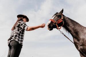 jovem feliz mulher dentro chapéu com dela cavalo dentro tarde pôr do sol claro. ao ar livre fotografia com moda modelo garota. estilo de vida humor. conceito do ao ar livre cavalgando, Esportes e lazer. foto