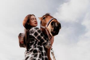 jovem feliz mulher dentro chapéu com dela cavalo dentro tarde pôr do sol claro. ao ar livre fotografia com moda modelo garota. estilo de vida humor. conceito do ao ar livre cavalgando, Esportes e lazer. foto