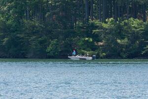 homem pescaria dentro uma barco em a lago foto
