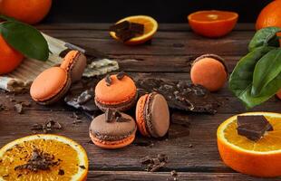 delicioso com sabor de chocolate macarons com laranja em uma Sombrio de madeira fundo foto