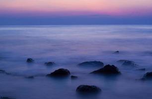 ondas suaves em uma praia rochosa à noite foto