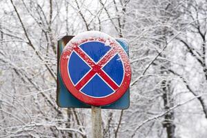 não em pé ou estacionamento rua placa coberto dentro neve. ensolarado inverno dia. vermelho e azul cor. foto